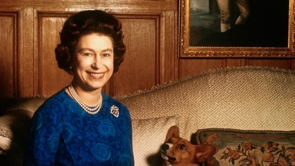 Queen Elizabeth II smiles radiantly during a picture-taking session in the salon at Sandringham House in 1970. Her pet dog looks up at her. These photos were taken in connection with the royal family's planned tour of Australia and New Zealand. Photo / Getty via NZ Herald